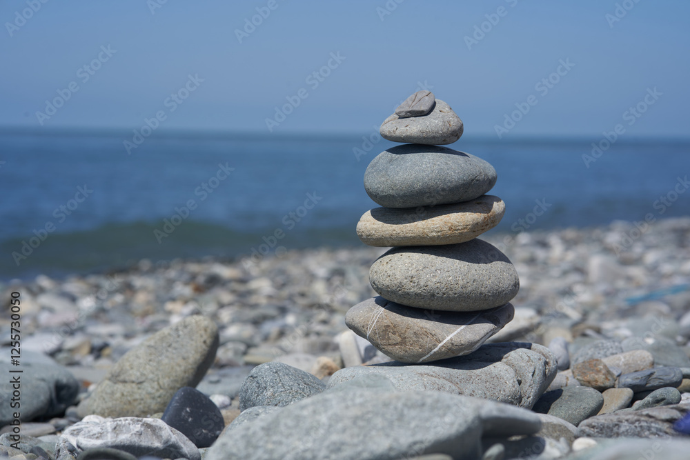 Balancing rocks on a pebble beach during sunset. Smooth pebbles on the beach against the background of the sea and sunlight, creating a side effect on the water. High quality photo Balancing rocks on a pebble beach during sunset. Smooth pebbles on the beach against the background of the sea and sunlight, creating a side effect on the water. High quality photo