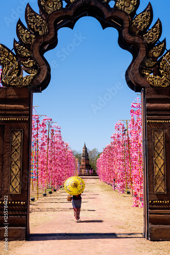 Young female tourist visits colorful flags at Phra That Yakhu, Kalasin Province, Thailand.