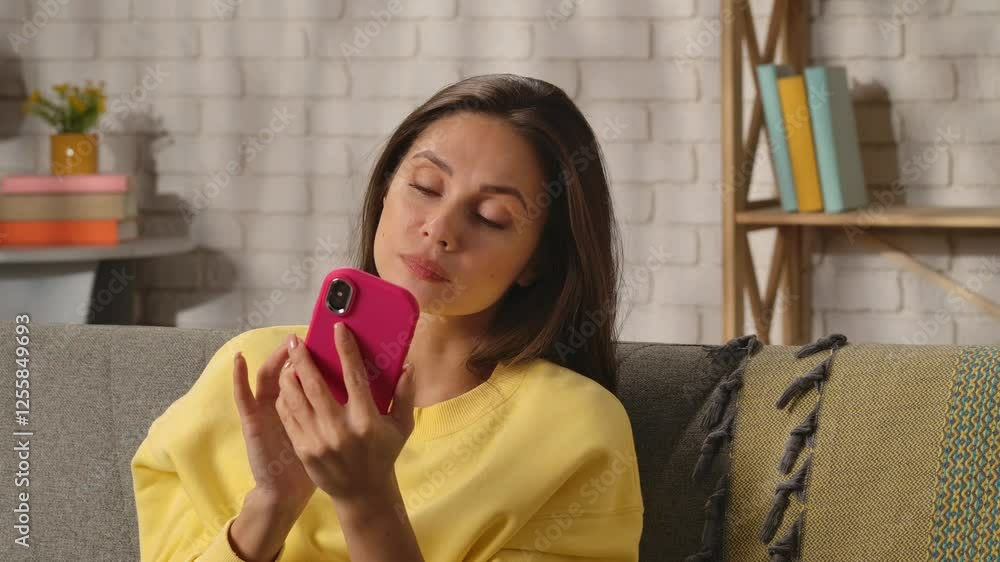 Young woman spending day at home sitting on sofa in the living room, holding smartphone scrolling social media, seeing interesting post, surprised good expression. Young woman spending day at home sitting on sofa in the living room, holding smartphone scrolling social media, seeing interesting post, surprised good expression.
