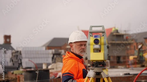 Construction worker using surveying equipment for measurement on site in urban area during overcast day