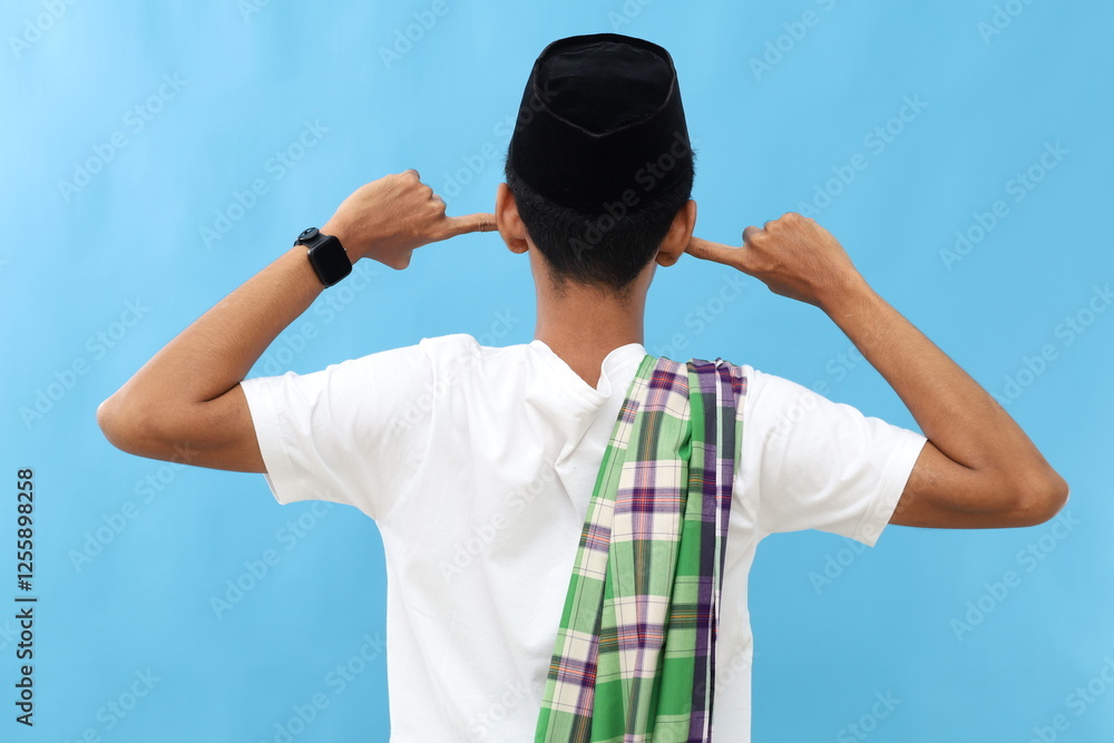 Back view of asian muslim man standing while covering ears with his fingers Back view of asian muslim man standing while covering ears with his fingers
