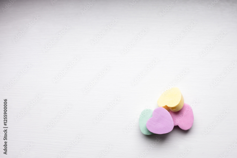 close-up of a pile of pastel candy hearts in pink, green, yellow and purple on w white wooden surface with copy space available close-up of a pile of pastel candy hearts in pink, green, yellow and purple on w white wooden surface with copy space available