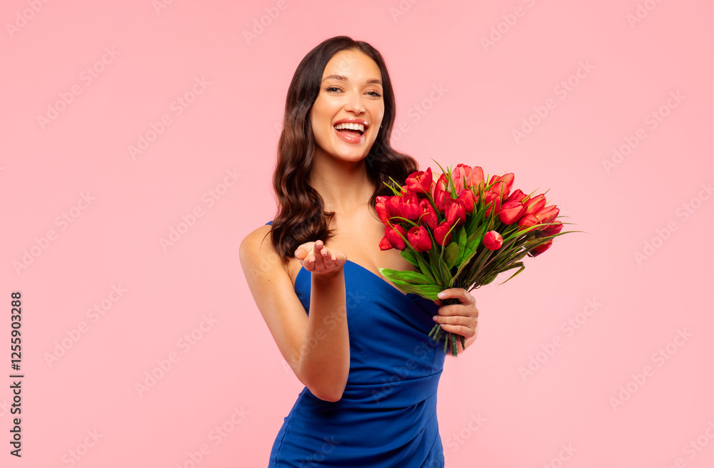 Excited elegant woman with red tulips smiling at camera, posing on pink studio background, ready for Woman's Day celebration Excited elegant woman with red tulips smiling at camera, posing on pink studio background, ready for Woman's Day celebration