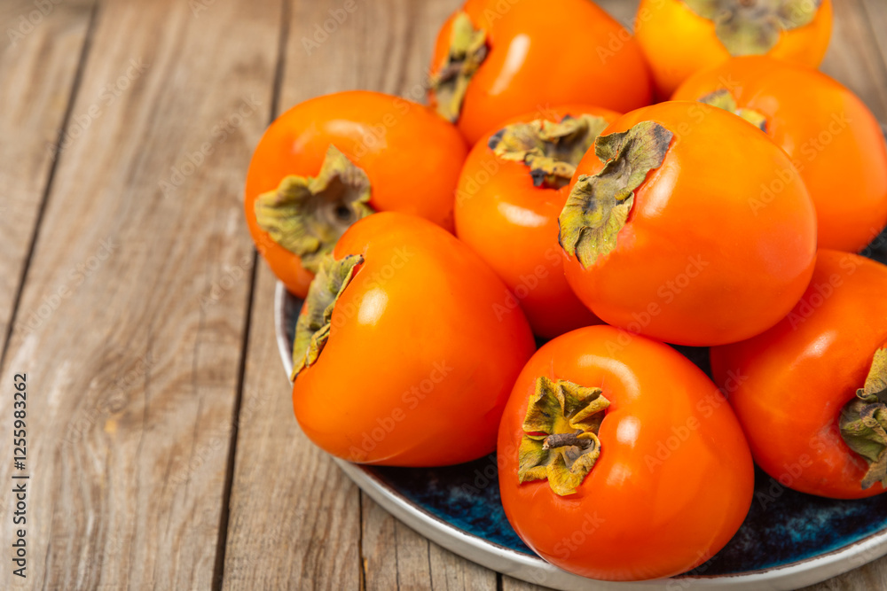 Persimmon on textured wooden background. Persimmon fruit. A piece of ripe, juicy, sweet persimmon fruit. Vegan. Orchard. Close-up. Space for text. Copy space. Persimmon on textured wooden background. Persimmon fruit. A piece of ripe, juicy, sweet persimmon fruit. Vegan. Orchard. Close-up. Space for text. Copy space.