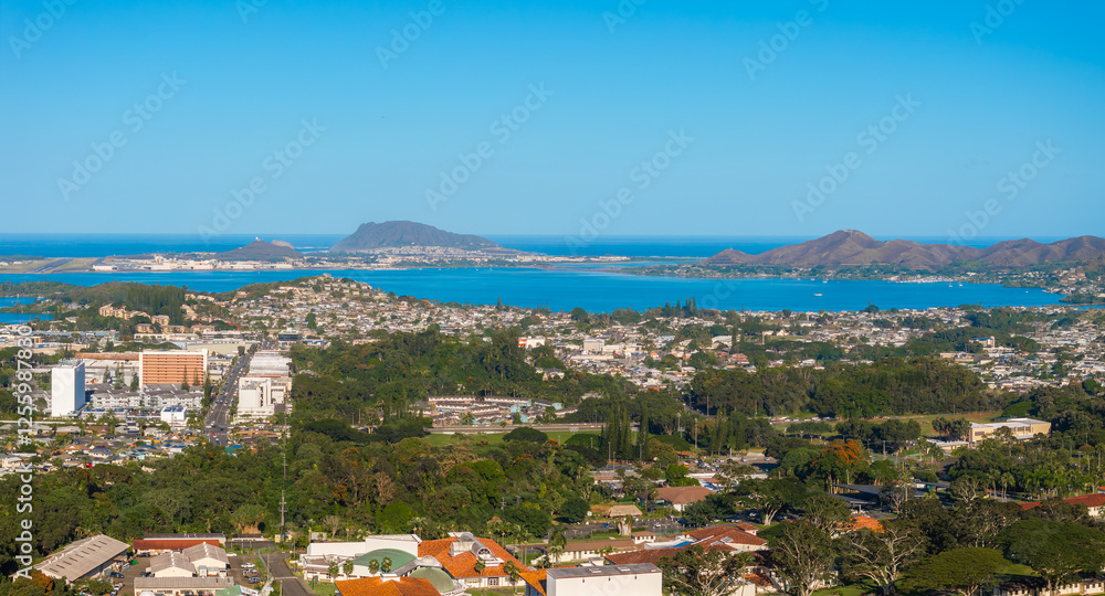Aerial view of Oahu, Hawaii, featuring urban areas, Kaneohe Bay, Mokapu Peninsula, and the Ko olau mountain range under a clear blue sky. Aerial view of Oahu, Hawaii, featuring urban areas, Kaneohe Bay, Mokapu Peninsula, and the Ko olau mountain range under a clear blue sky.
