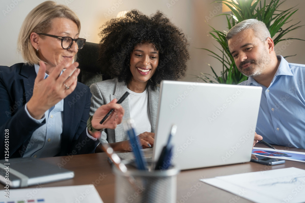 Fototapeta premium Three busy happy middle aged professional business man and two women executive leaders team using laptop working on computer at work desk having conversation on financial project at meeting in office.