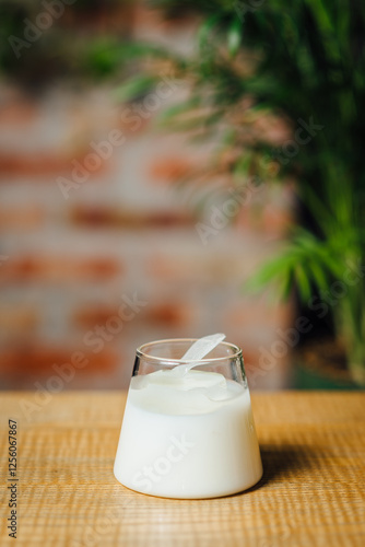 Wite cocktail in a glass, featuring gin, fresh citrus mix, vanilla syrup, and cream. Served over ice with a garnish on the bar counter, in warm bar ambiance, vertical image photo