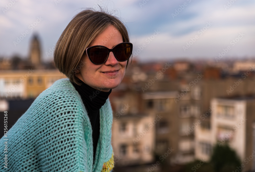 Portrait of an attractive thirty year old white sitting woman with sunglasses posing on her rooftop, Brussels, Belgium Portrait of an attractive thirty year old white sitting woman with sunglasses posing on her rooftop, Brussels, Belgium