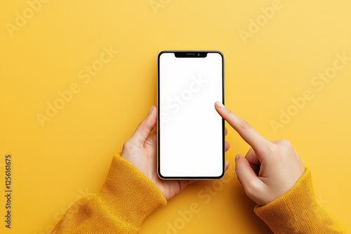 Fondo amarillo visto desde arriba con manos y ersey de mujer sosteniendo un telefono movil con la pantalla vcia en color blanco