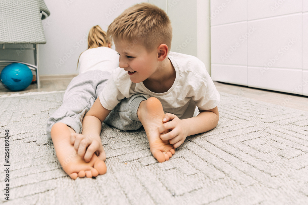 Naklejka premium the children are wrapped in a blanket and tickling each other's heels on the bed. Family having fun at home. Leisure