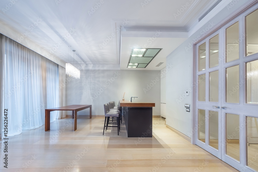 Fototapeta premium The kitchen area in the apartment is decorated in white. Double-leaf door with glass windows. Stylish ceiling lamp above the dining table.