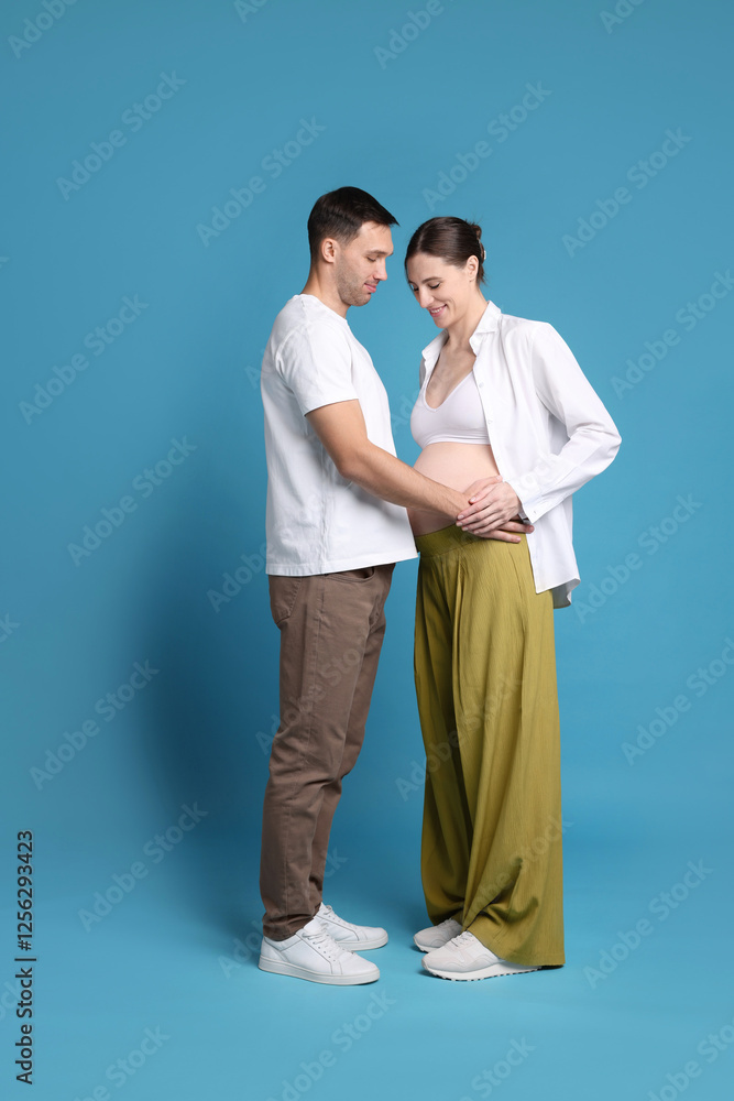 Pregnant woman and her husband on blue background Pregnant woman and her husband on blue background