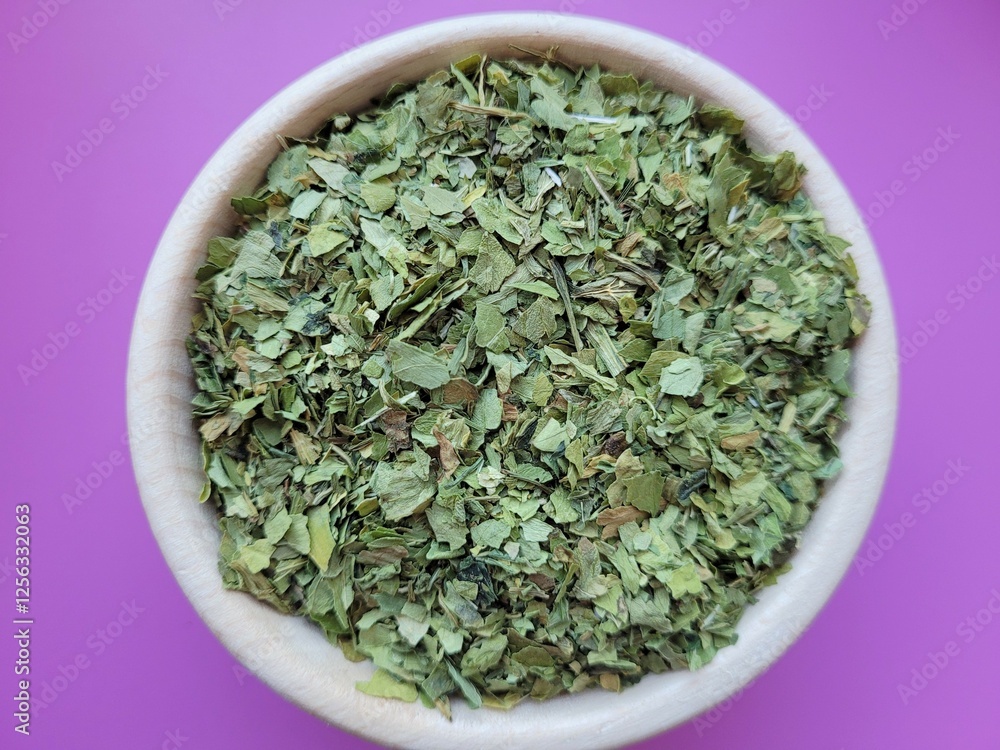 Dried pile of lovage leaves on a violet background. Dried pile of lovage leaves on a violet background.