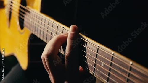 Young musican man checking strings of acoustic guitar close-up. Male guitarist tuning sound of musical instrument. 