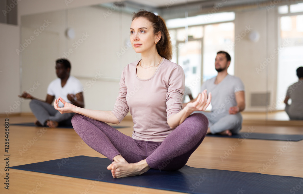 Multiethnic group of people exercising lotus asana in gym. Multiethnic group of people exercising lotus asana in gym.