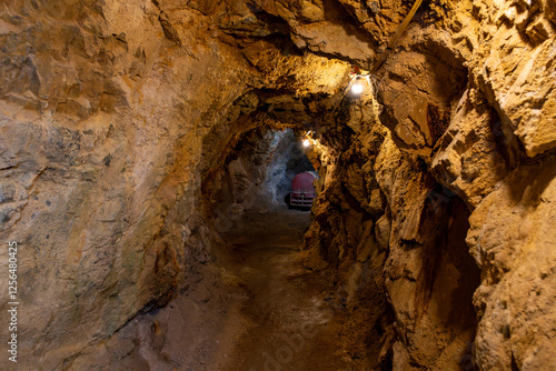 Exploring the historic underground gold mine tunnel illuminated by dim lights, revealing rugged rock formations in a remote location