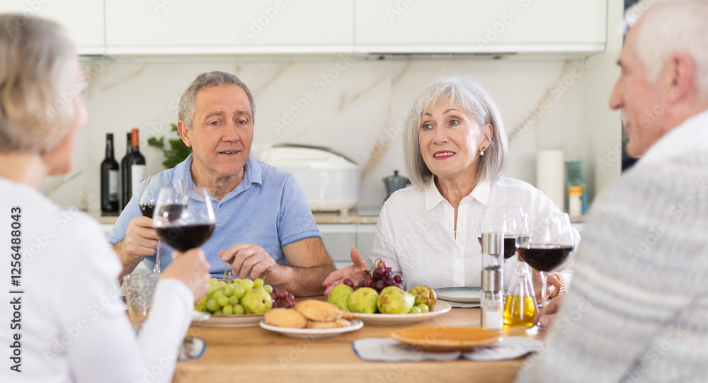 Couples of elderly women and men chatting and drinking wine at table.. Couples of elderly women and men chatting and drinking wine at table..