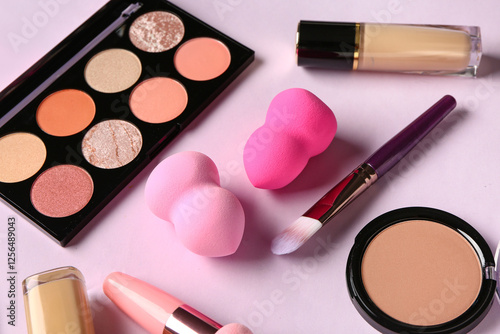 Set of decorative cosmetics and makeup sponges on lilac background, closeup