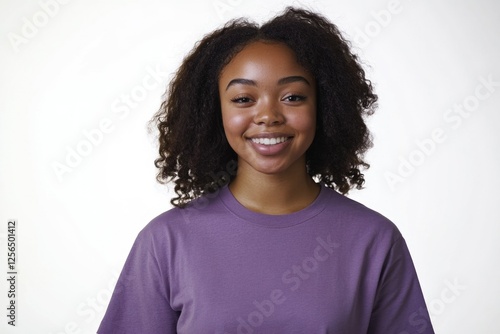 A cheerful woman with curly hair, wearing a purple top and standing against a white background. photo