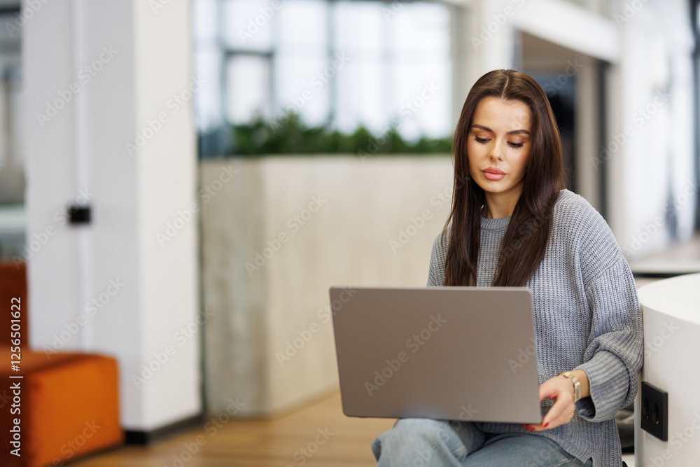 Young woman smiling while working with laptop in office Young woman smiling while working with laptop in office