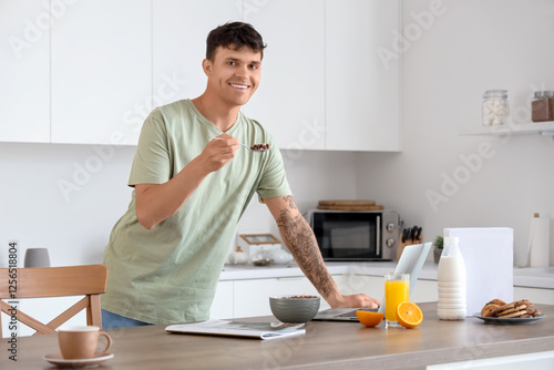 Young man with laptop eatin...