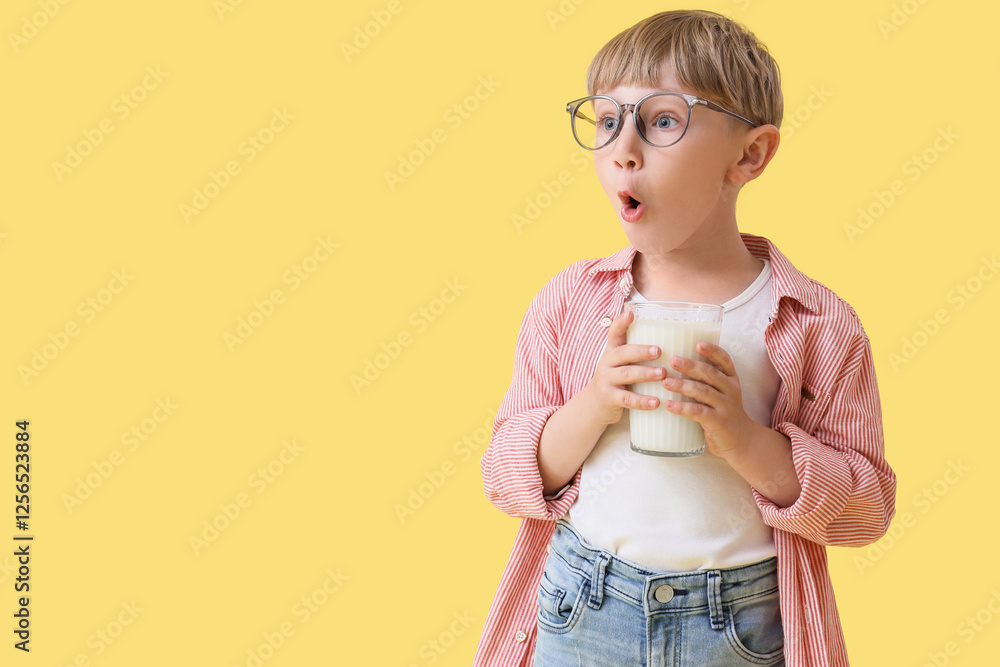Surprised little boy with glass of milk on yellow background Surprised little boy with glass of milk on yellow background