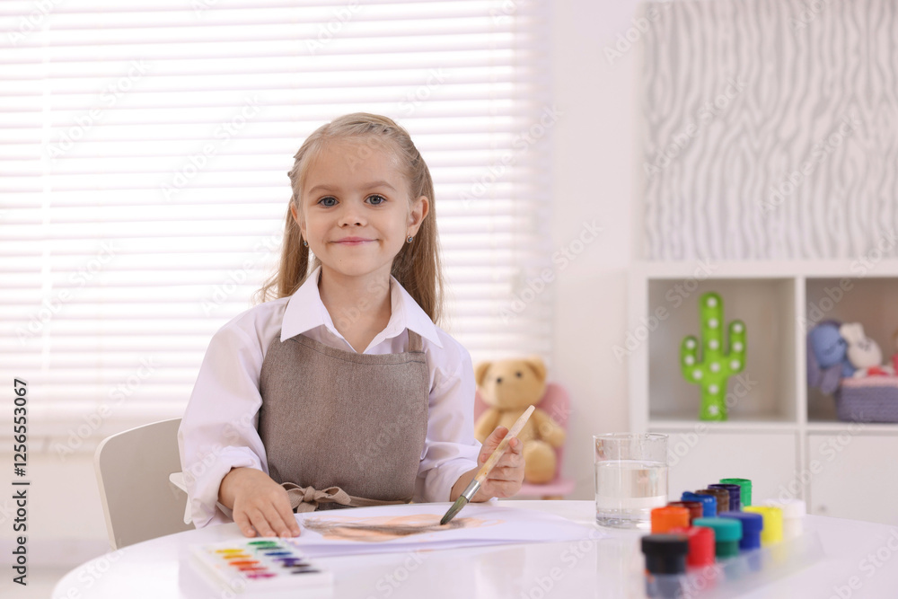 Cute girl drawing at white table in kindergarten Cute girl drawing at white table in kindergarten