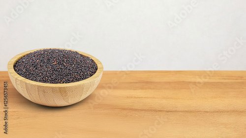 A wooden bowl filled with black mustard seeds sits on a wooden surface, highlighting a popular spice used in various cuisines. The tiny, dark seeds are known for their strong, pungent flavor.
 photo