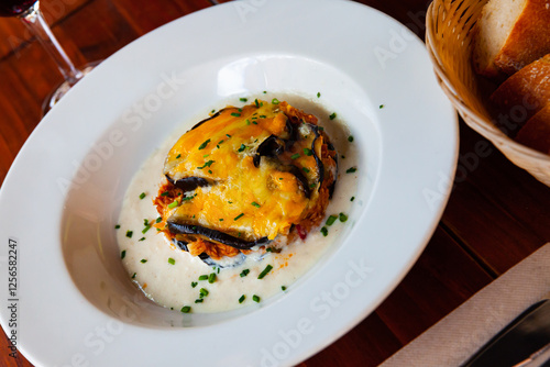 Appetizing moussaka - baked aubergine with tuna, bechamel sauce and golden crust of grated cheese on white play photo