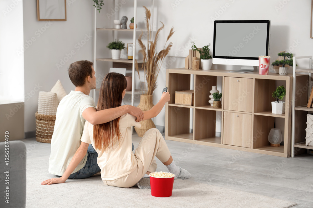 © Pixel-Shot - Young couple watching TV at home, back view