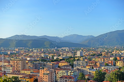 View over the city of Brescia as seen from Cidneo hill with mountains in the back and clear blue sky on a summer day in Italy