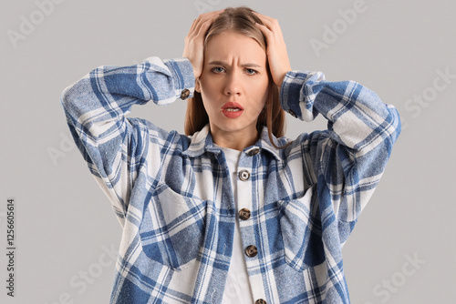 Worried young woman on grey...