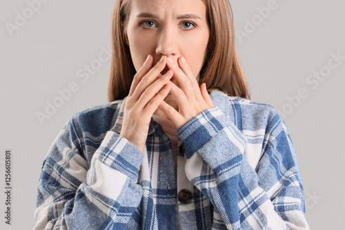 Worried young woman on grey...