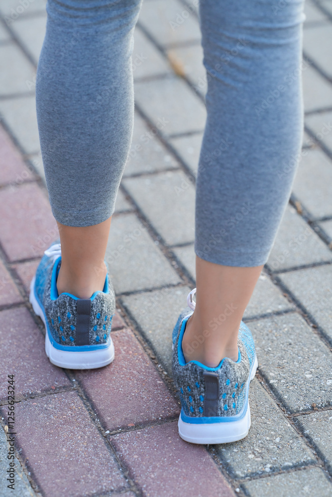 Person walking on a paved sidewalk wearing athletic attire and colorful running shoes during daytime Person walking on a paved sidewalk wearing athletic attire and colorful running shoes during daytime