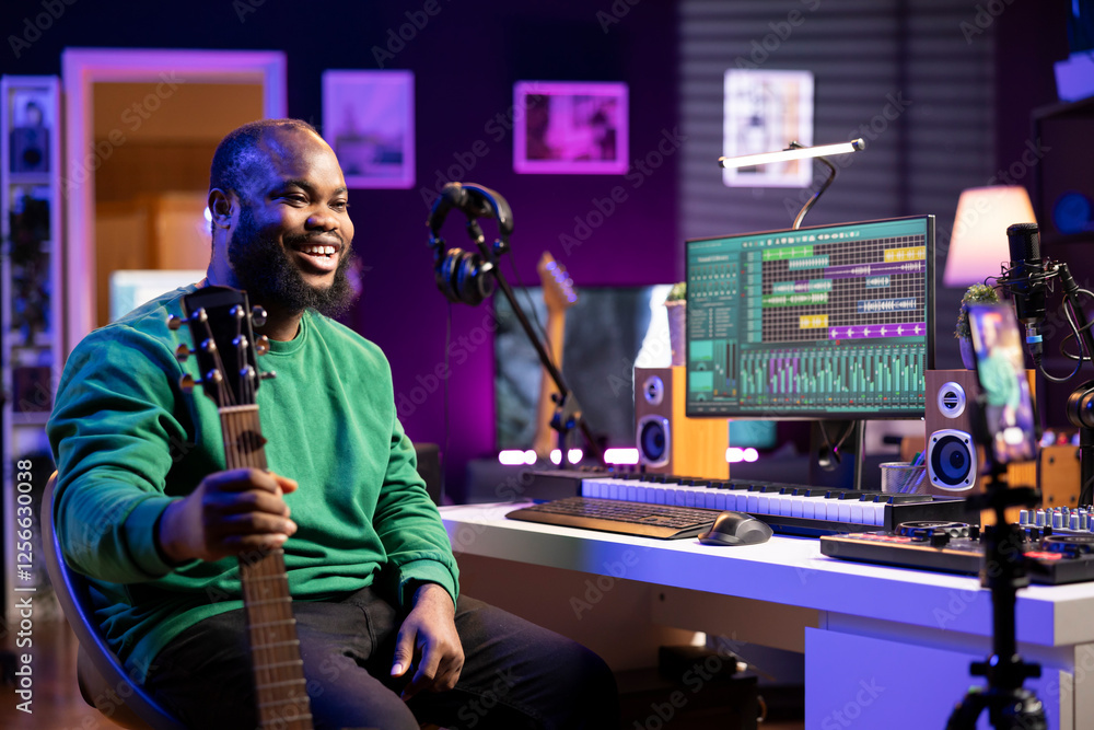 Obraz premium Musical composer hosting online guitar lessons with tutorial video on smartphone, recording himself playing acoustic instrument. Young artist teaching people how to play accords on strings, vlog.