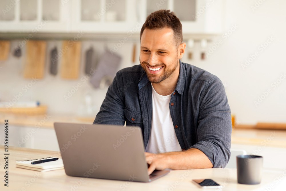 Cozy work at home Young happy man independent contractor working on laptop and smiling, enjoying remote work, sitting at home kitchen interior, free space Cozy work at home Young happy man independent contractor working on laptop and smiling, enjoying remote work, sitting at home kitchen interior, free space