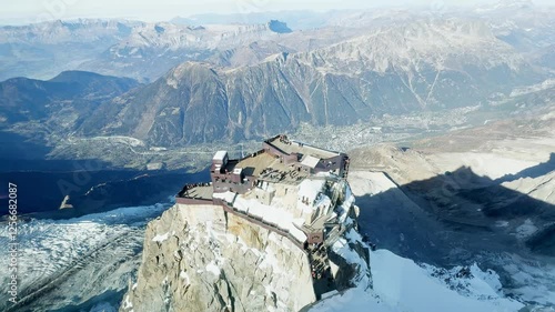 Breathtaking view from the highest point of Aiguille du Midi with the glass skywalk, overlooking the lower cable car station, Chamonix valley, and the stunning peaks of the French Alps.