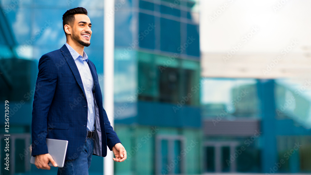 Happy young arab businessman walking from office, holding notepad, looking at copy space and smiling, panorama. Successful muslim manager going to business meeting, modern office building background Happy young arab businessman walking from office, holding notepad, looking at copy space and smiling, panorama. Successful muslim manager going to business meeting, modern office building background