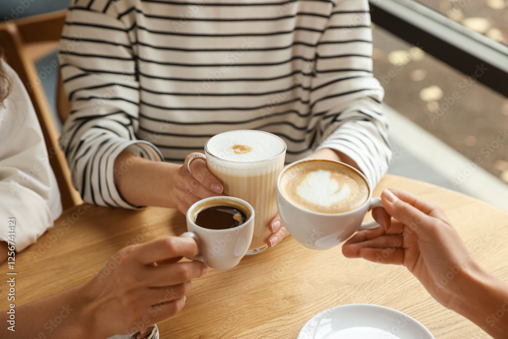 Women with cups of delicious coffee drinks at wooden table in cafe, closeup Women with cups of delicious coffee drinks at wooden table in cafe, closeup