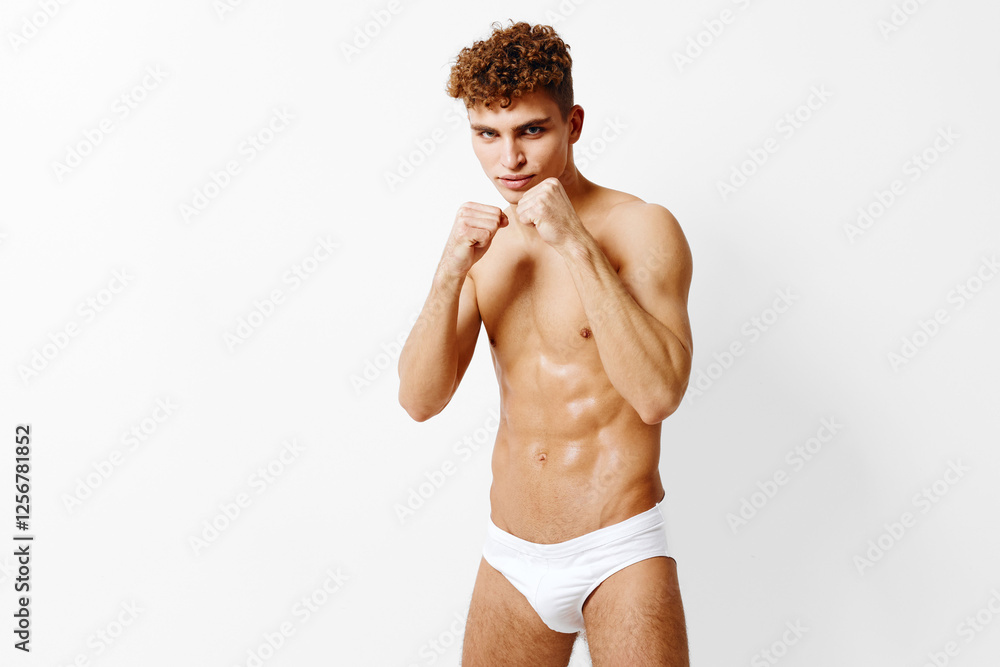 Fototapeta premium Confident young male boxer posing in white underwear, showcasing strength and athleticism. Fitness and sports concept with a neutral background.