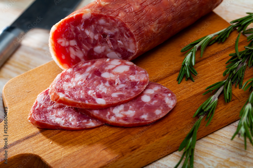 Salchichon, traditional spanish dry cured pork sausage on wooden table Salchichon, traditional spanish dry cured pork sausage on wooden table