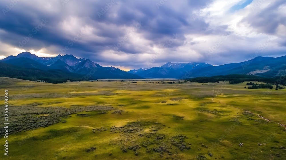 Fototapeta premium Stunning Aerial View of Vast Green Valley Surrounded by Majestic Mountains Under Dramatic Cloudy Sky : Generative AI