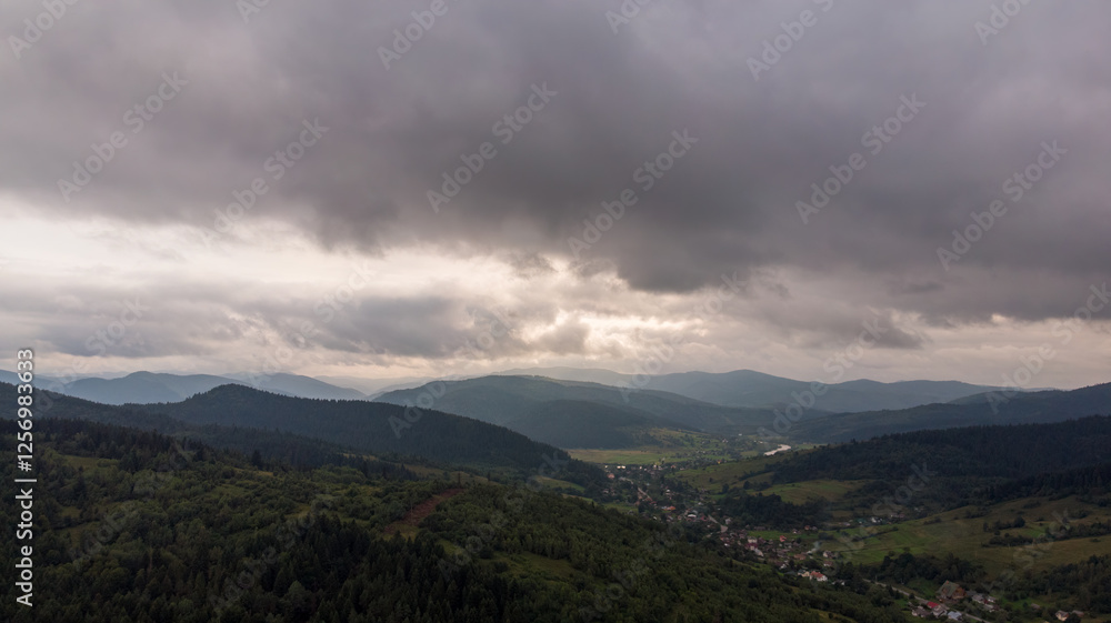 Aerial View Of Majestic Mountains Under A Cloudy Sky At Sunset. The Golden Light Illuminates The Peaks, Creating A Stunning Contrast Between The Dramatic Clouds And Rugged Landscape. Aerial View Of Majestic Mountains Under A Cloudy Sky At Sunset. The Golden Light Illuminates The Peaks, Creating A Stunning Contrast Between The Dramatic Clouds And Rugged Landscape.