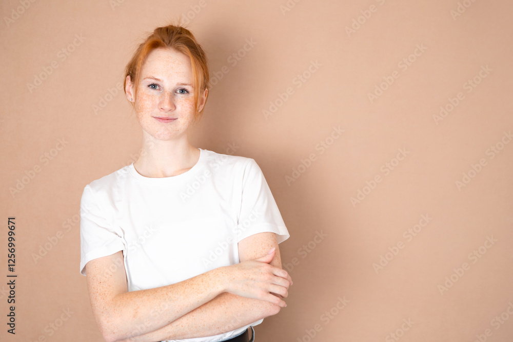 Portrait of a red-haired young woman with freckles on a beige background. Space for text. Natural colors. Beautiful skin and hair. Smile Portrait of a red-haired young woman with freckles on a beige background. Space for text. Natural colors. Beautiful skin and hair. Smile