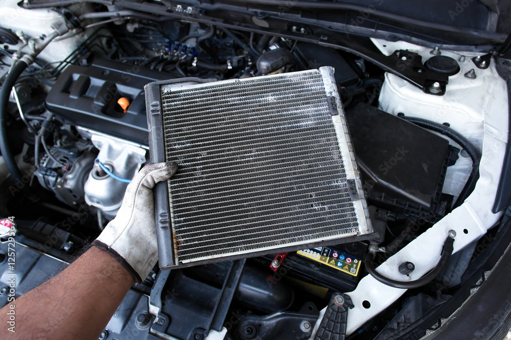 Mechanic holding radiator or evaporator of car air conditioner during car maintenance , oil gear cooler , Car maintenance concept