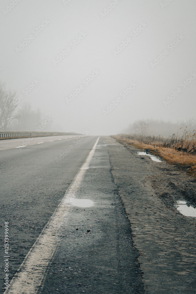 Empty highway in the fog. Bad weather on the road. Road on foggy day in perspective with copy space. Driving conditions concept. Ghostly misty road. Caution and danger on the road. Moody weather