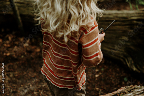 Child holding a pocket knife building a forest cabin photo