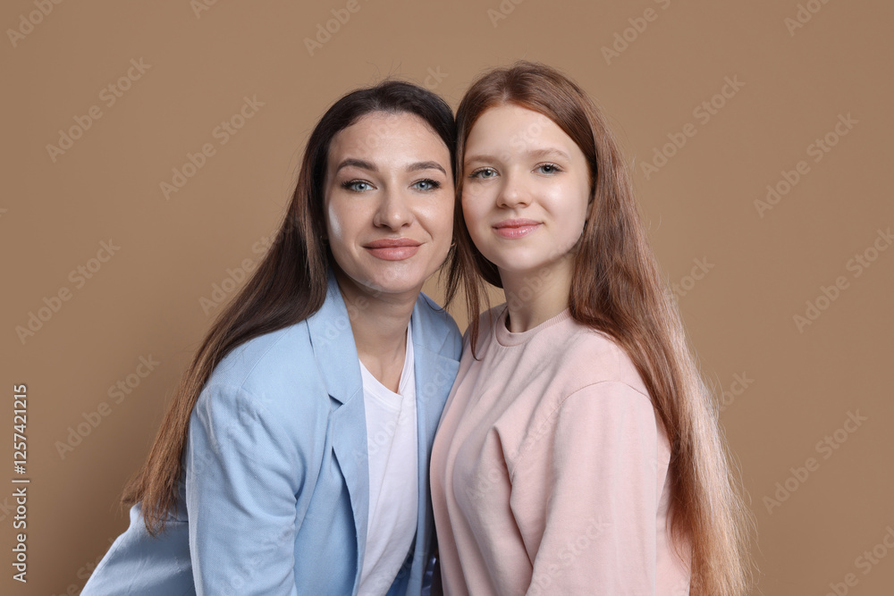 Portrait of beautiful mother with teenage daughter on dark beige background Portrait of beautiful mother with teenage daughter on dark beige background