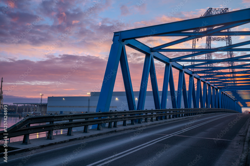 Industrial landscape-truss bridge leading to marine industry production buildings during spectacular sunrise