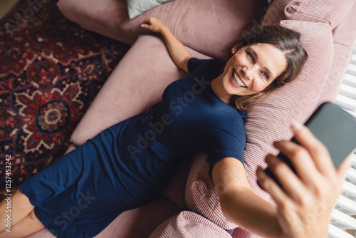 Happy woman attending video call through smart phone at home